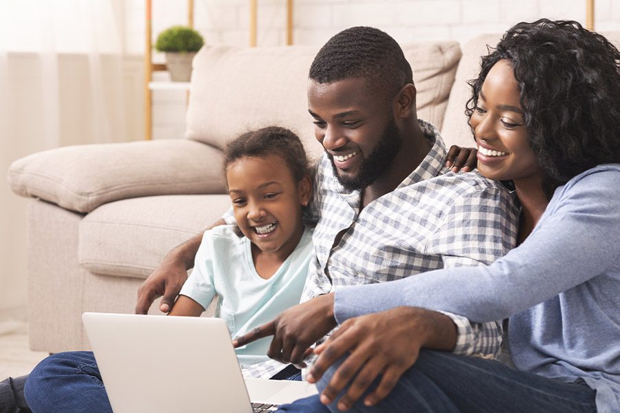 Blog - Joyful Family Using a Laptop at Home Together While Sitting on the Floor in Front of Their Couch