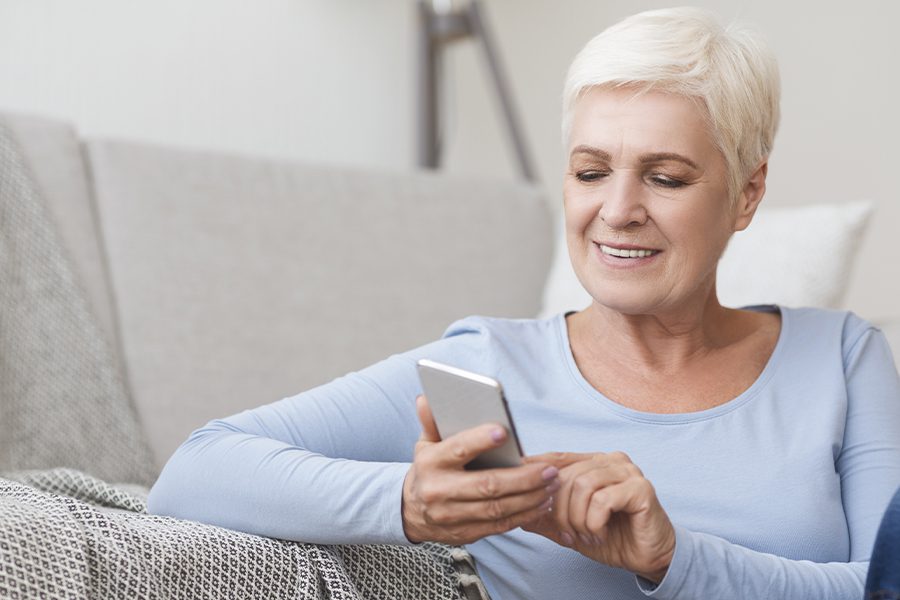 Client Center - Image of Senior Woman Using Her Phone to Easily Access Important Insurance Account Information